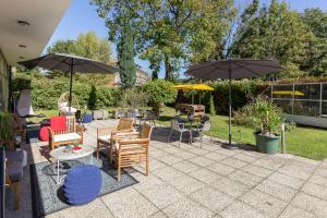 eine Terrasse mit Tischen, Stühlen und Sonnenschirmen in der Unterkunft das West in Sankt Kanzian am Klopeiner See