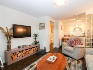 a living room with a couch and a tv on a wall at The Bothy in Stonehaven