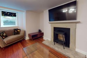 a living room with a couch and a television above a fireplace at The Nook at Nydsley Hall - Featuring Patio & Hot tub in Pateley Bridge