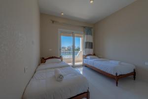 two beds in a room with a window at Joubal 3BR Villa Private Pool next to Marina in Hurghada +37 photos