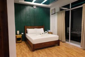 1 dormitorio con 1 cama con pared verde en MANANQUIL TRAVEL LODGE en El Nido