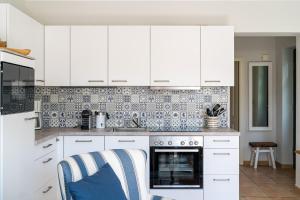 a kitchen with white cabinets and a blue and white tile wall at Strandhaus Düne 19 - Freude in Neuhaus