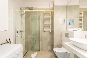 een badkamer met een douche, een toilet en een wastafel bij Ambria Apartments Ułańska in Świnoujście +40 foto's