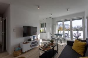een woonkamer met een bank en een flatscreen-tv bij Ambria Apartments Ułańska in Świnoujście