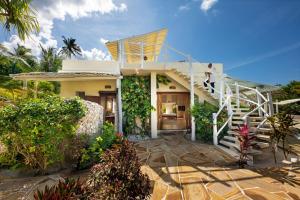 
a house with a balcony and a staircase leading to a garden at Zanzibar White Sand Luxury Villas & Spa - Relais & Chateaux in Paje
