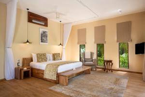 a room with a bed, table, chairs and a window at Zanzibar White Sand Luxury Villas & Spa - Relais & Chateaux in Paje