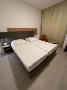 a bedroom with a large bed with white sheets at Hotel Mintarder Wasserbahnhof in Mülheim an der Ruhr