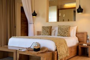 1 dormitorio con 1 cama grande y espejo en Zanzibar White Sand Luxury Villas & Spa - Relais & Chateaux en Paje