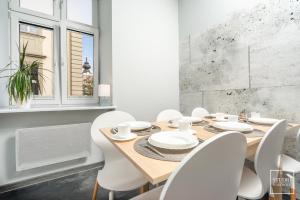 a dining room with a wooden table and white chairs at Apartament Papieski in Wadowice