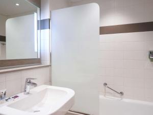 a white bathroom with a sink and a mirror at Mercure Le Mans Batignolles in Le Mans