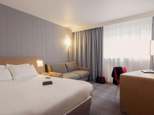 una camera d'albergo con letto e divano di Novotel Roissy Saint Witz a Saint-Witz