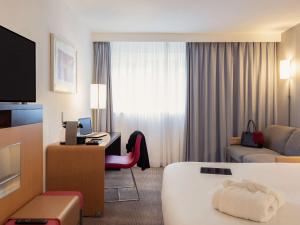 サン・ヴィッツにあるNovotel Roissy Saint Witzのベッドとデスクが備わるホテルルームです。