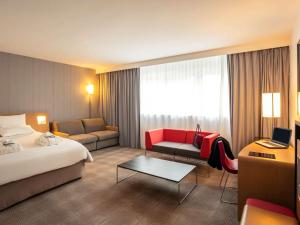 a hotel room with a bed and a couch at Novotel Roissy Saint Witz in Saint-Witz