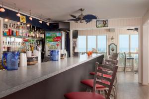 a bar with red chairs and bottles of alcohol at Surfside Beach Oceanfront Hotel in Myrtle Beach