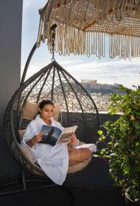 a man sitting in a hammock reading a book at Play Theatrou Athens in Athens