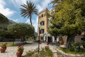 a building with a palm tree in front of it at Hotel Castello Monticello in Giglio Porto