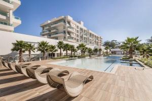 a resort with a swimming pool and chairs and a building at Atlântida Green Square - 606B in Xangri-lá
