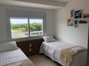 a bedroom with two beds and a window at Atlântida Green Square - 606B in Xangri-lá +35 photos