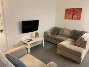a living room with two couches and a flat screen tv at Glenfinnan - Two Bedroom Apartment in Fife