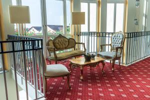ein Hotelzimmer mit zwei Stühlen und einem Tisch und ein Zimmer mit Fenstern in der Unterkunft Hotel Garni Arcis in Gomaringen