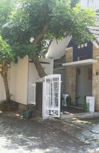 a white gate in front of a house with a tree at Cipta Guesthouse in Yogyakarta