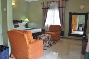 a bedroom with a bed and a chair and a mirror at Home Bliss Hotel- Fort portal Uganda in Fort Portal