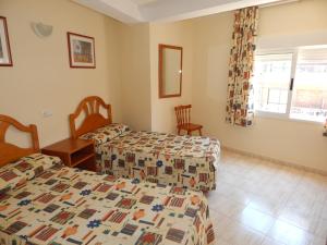 
a bedroom with two beds and two lamps at Apartamentos Avenida in Benidorm
