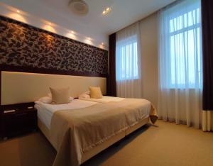 a bedroom with a large bed and two windows at Hotel Zamek Centrum in Szczecin