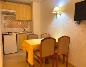 Residence Royal - Deluxe في Hammamet Sud: مطبخ مع طاولة مع كراسي وقطعة قماش صفراء