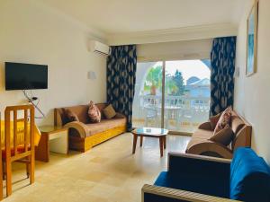 a living room with couches and a television and a balcony at Residence Royal - Deluxe in Hammamet Sud