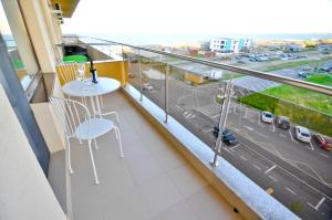 Un balcón con una mesa y sillas y una calle. en Summerland Happy Blue Apartments en Mamaia