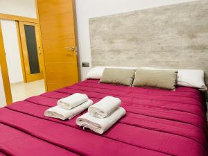 een groot bed met roze lakens en handdoeken erop bij Be Suites Centro in Granada