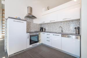a kitchen with white cabinets and a sink at House of Dalmatia in Pakoštane