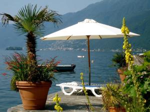 a white umbrella and a boat in the water at Ascona: Casa Rivabella in Ascona