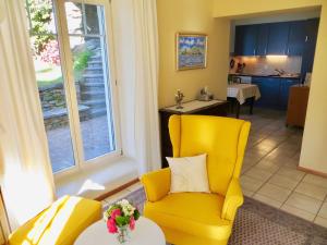 ein Wohnzimmer mit einem gelben Stuhl und einem Tisch in der Unterkunft Ascona: Casa Rivabella in Ascona