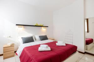 a bedroom with a large red bed with towels on it at Firenze Nova Comfortable Apartament with Terrace in Florence