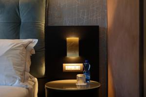 a table with a bottle on it next to a bed at Hotel Bell'arrivo by Dori in Peschiera del Garda