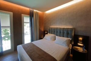 a bedroom with a large bed and a large window at Hotel Bell'arrivo by Dori in Peschiera del Garda