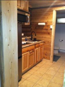 a kitchen with wooden walls and a sink and a refrigerator at Wapiti Lodge in Wapiti