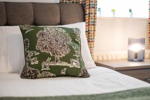 a bed with a green pillow with a tree on it at Alma Accommodation - TV in Every Bedroom! in Swansea