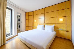 Un dormitorio con una gran cama blanca y una ventana en B-aparthotel Montgomery en Bruselas