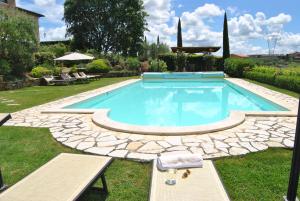 una piscina en un patio con un patio de piedra en Villa La Valiana - Full Estate in Montepulciano - HEATED POOL, en Valiano