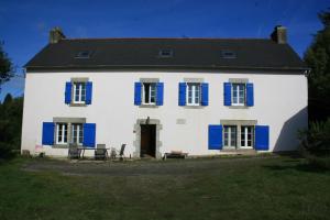 a large white house with blue shutters on it at Kercapitaine in Bannalec