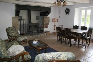 a living room with a fireplace and a table and chairs at Kercapitaine in Bannalec