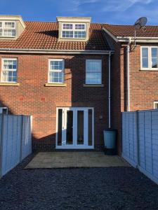 uma casa de tijolos com uma porta branca e uma cerca em Bullfinch House em Harleston