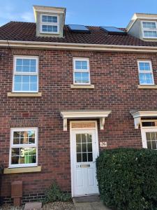 a red brick house with a white door at Bullfinch House in Harleston