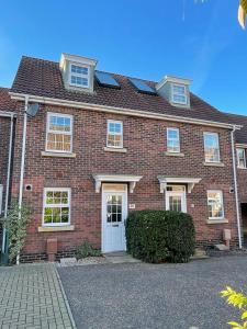 una casa de ladrillo rojo con puerta blanca en Bullfinch House, en Harleston