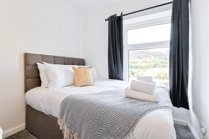 a bedroom with a bed with a window at Hilltop House - TV in Every Bedroom! in Merthyr Tydfil