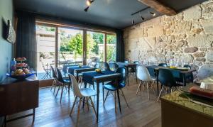 a restaurant with blue tables and chairs and a stone wall at Os Lambráns in Padrón