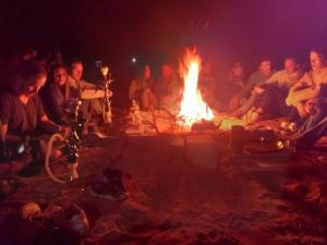 a group of people sitting around a large fire at Star City Camp wadirum in Wadi Rum